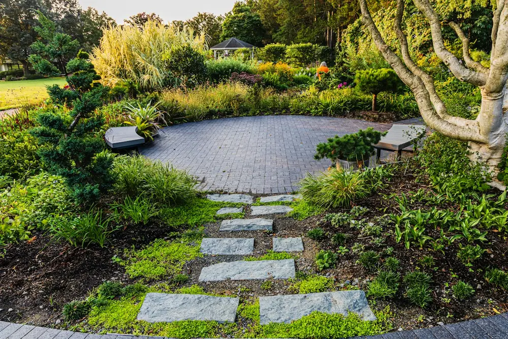 Gestalteter Garten mit Trittplatten, Pflanzbeeten und gepflastertem Sitzplatz