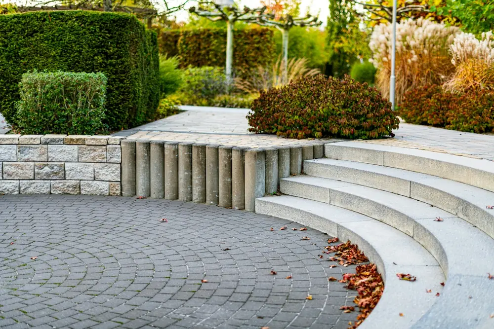 Saubere Pflasterfläche mit Natursteinstufen in einer Gartenanlage